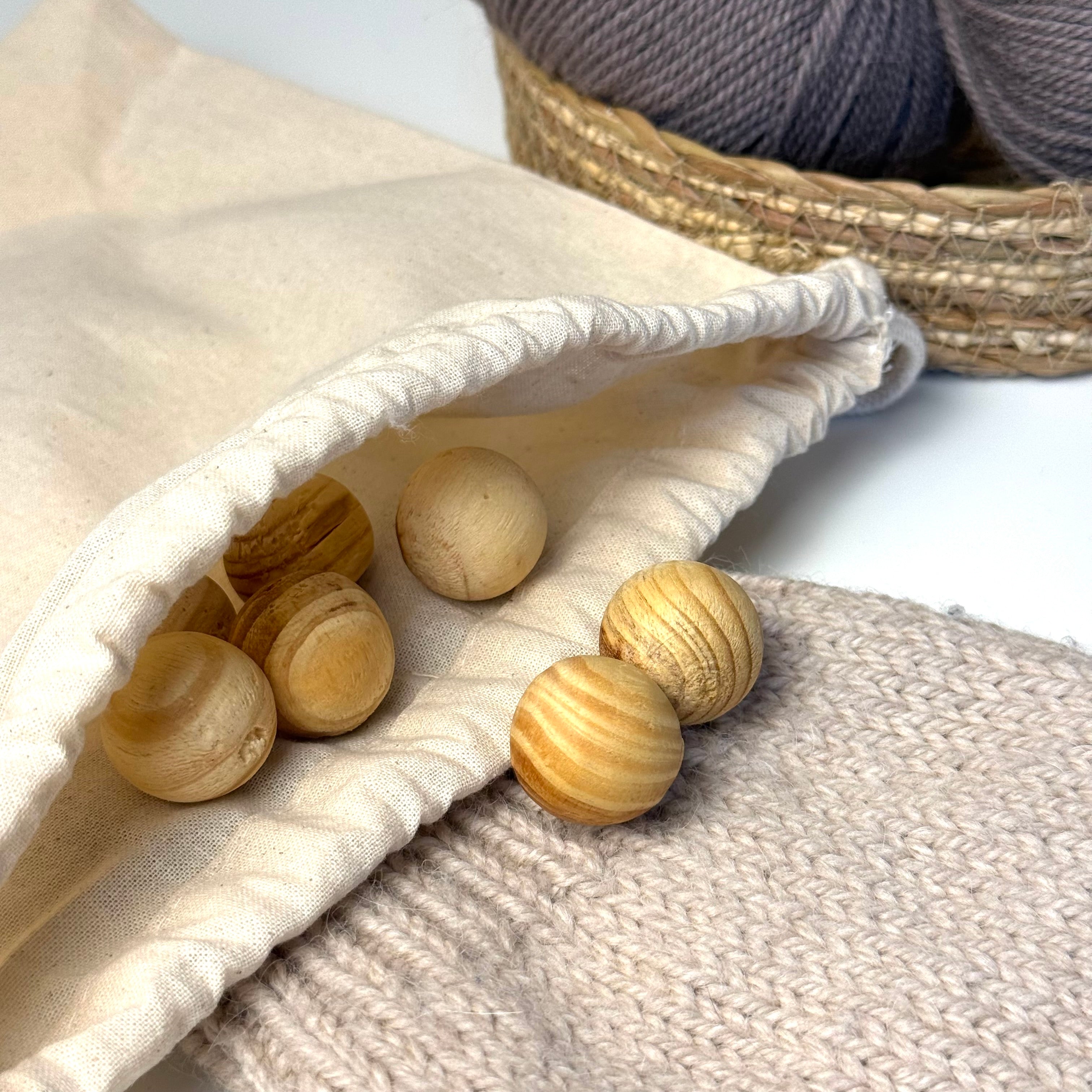 Cedar moth balls in a cotton drawstring bag and a knitted garment. Balls of yarn in the background